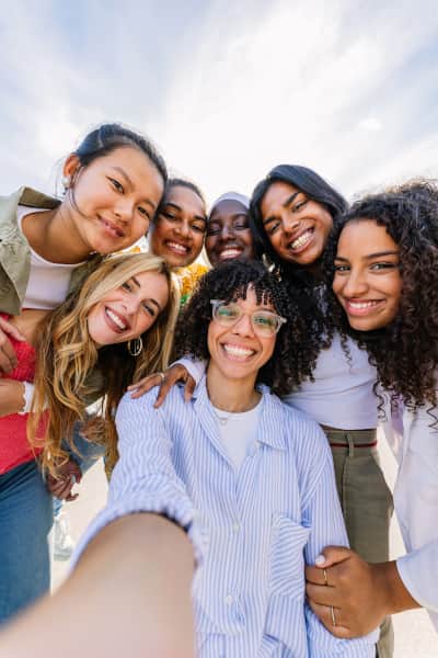 Group of young female friends taking a selfie, smiling at the camera together.
