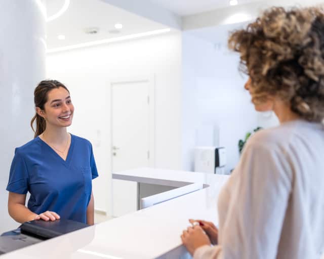 A young woman checking in at reception for a medical office.